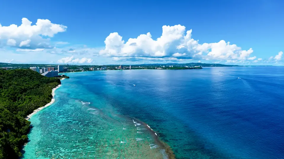 Guam's Tumon Bay with deep green and blue water and cityscape in the distance