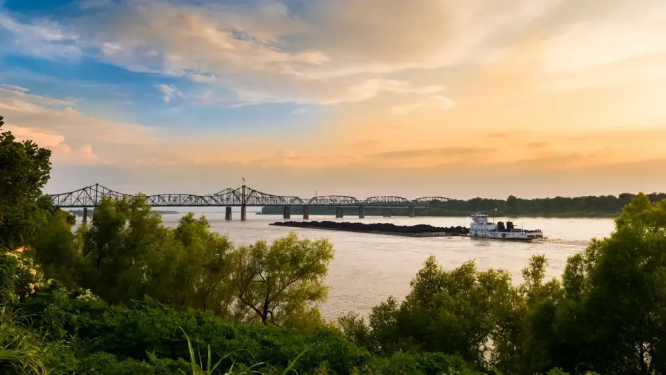 Mississippi river bank with river boat and cantilevered truss bridge in the background